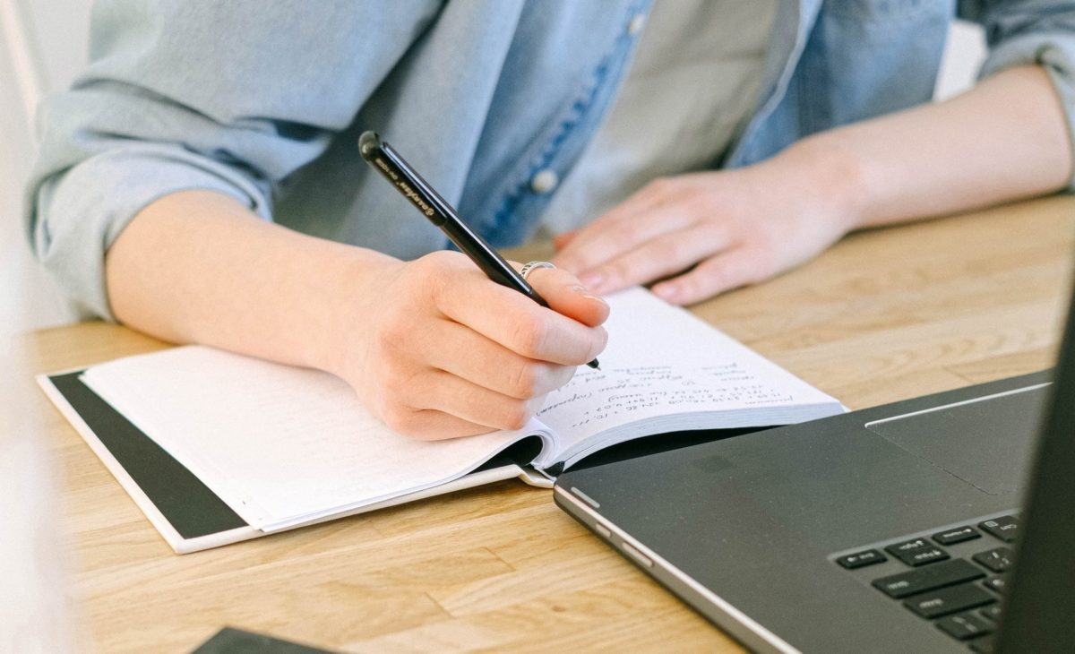 distant worker making notes by the laptop. Photo: Pexels